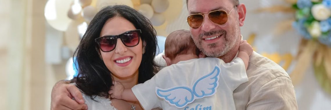 A joyful family celebrating a special occasion with their baby wearing an angel-themed shirt.